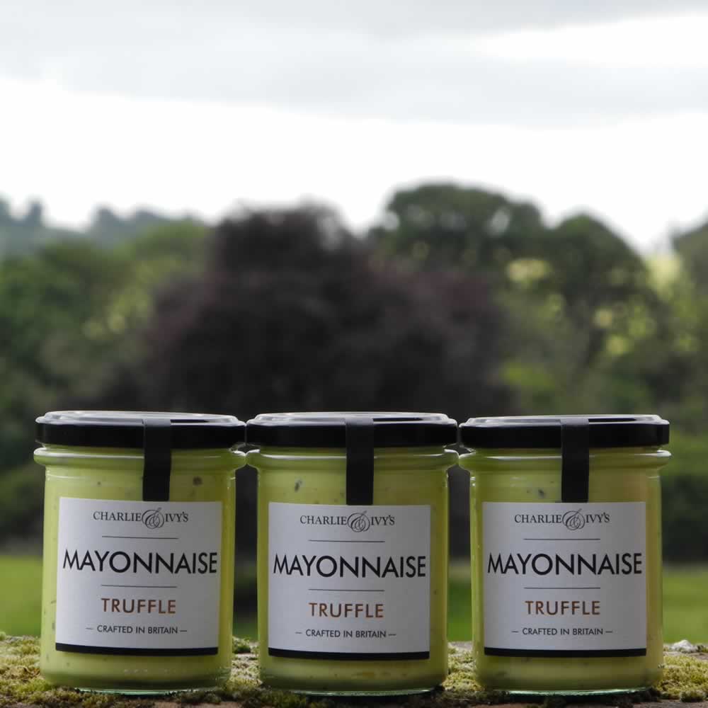 Three 190g jars of Charlie & Ivy's Truffle Mayonnaise with scenic countryside background