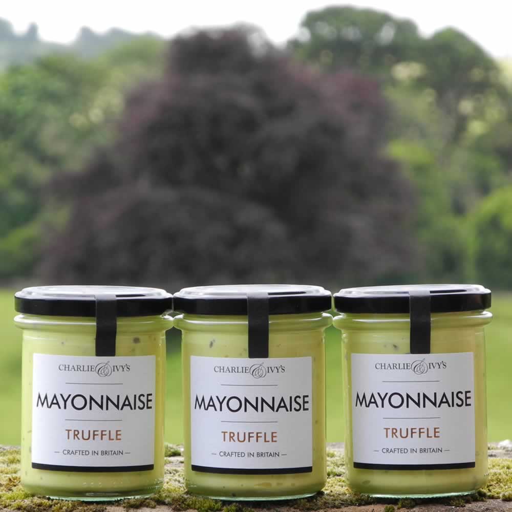 Three 190g jars of Charlie & Ivy's Truffle Mayonnaise with scenic countryside background