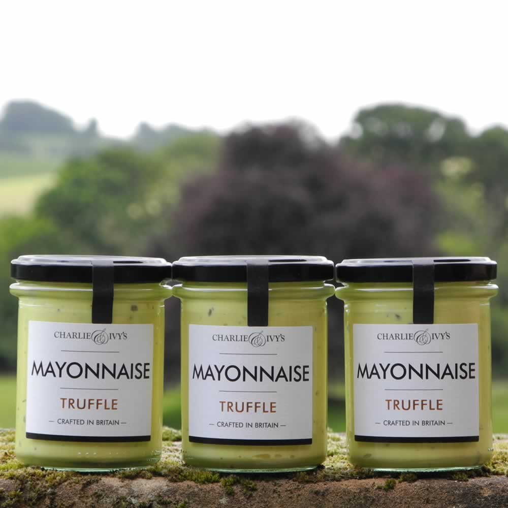 Three jars of Charlie & Ivy's Truffle Mayonnaise with scenic countryside background